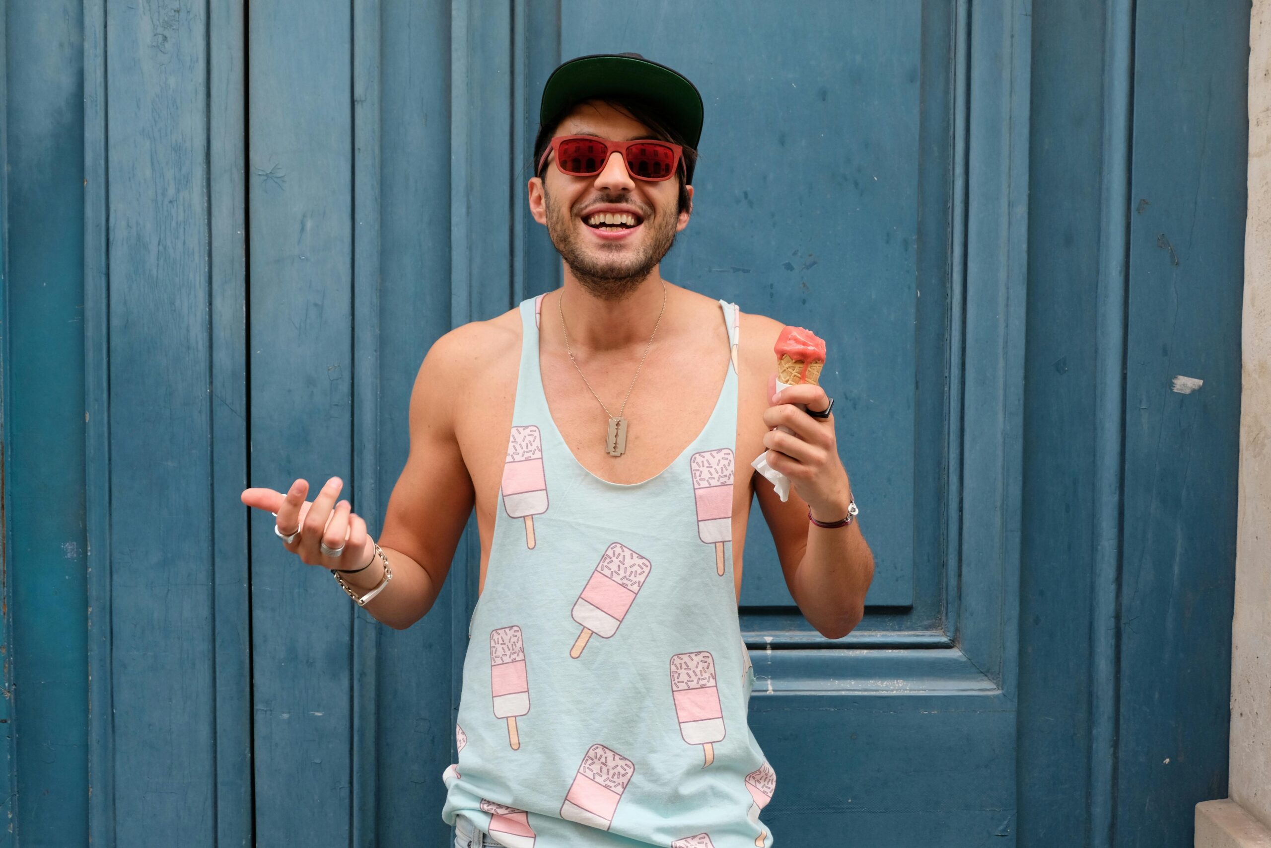 Happy man in Paris enjoying ice cream against a blue door. Fashionable and fun summer vibe.